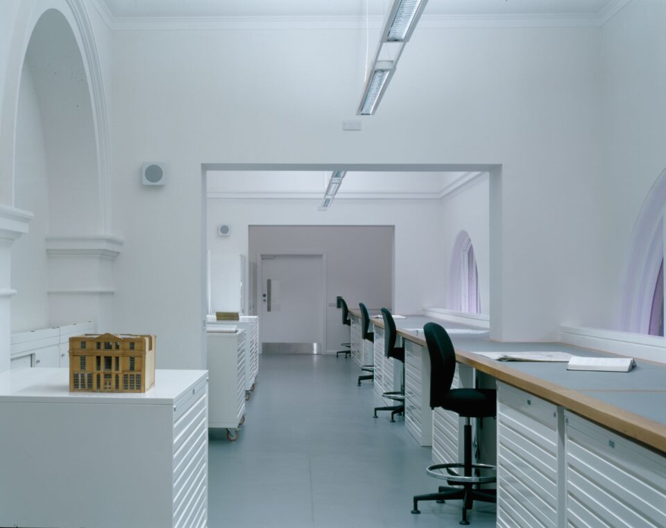 Long room with arched bays and windows in which desks and chairs can be seen at the right