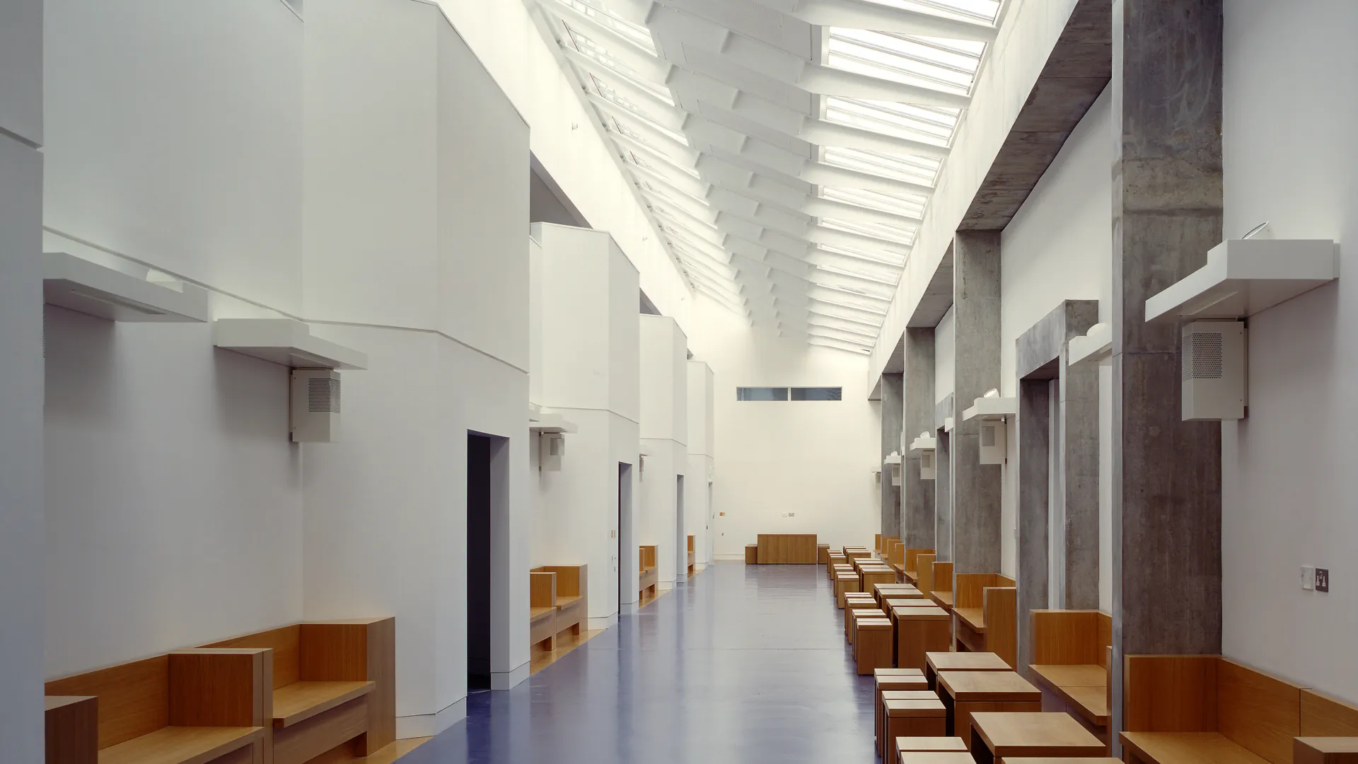 Interior of the Law Department of the London Metropolitan University designed by Wright and Wright Architects showing a long white hall with skylights and timber furniture.