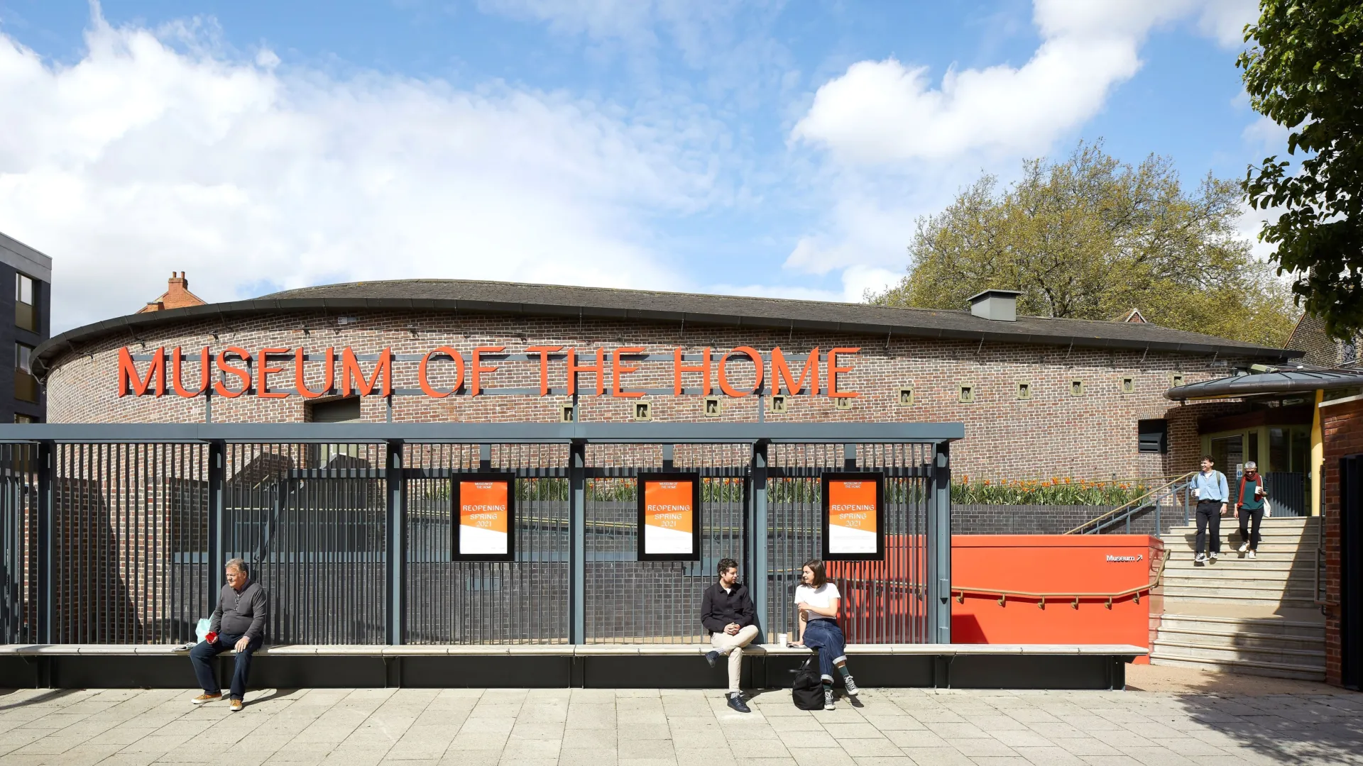 Entrance to Museum of the Home with people sitting on a bench in the foreground in Hackney London