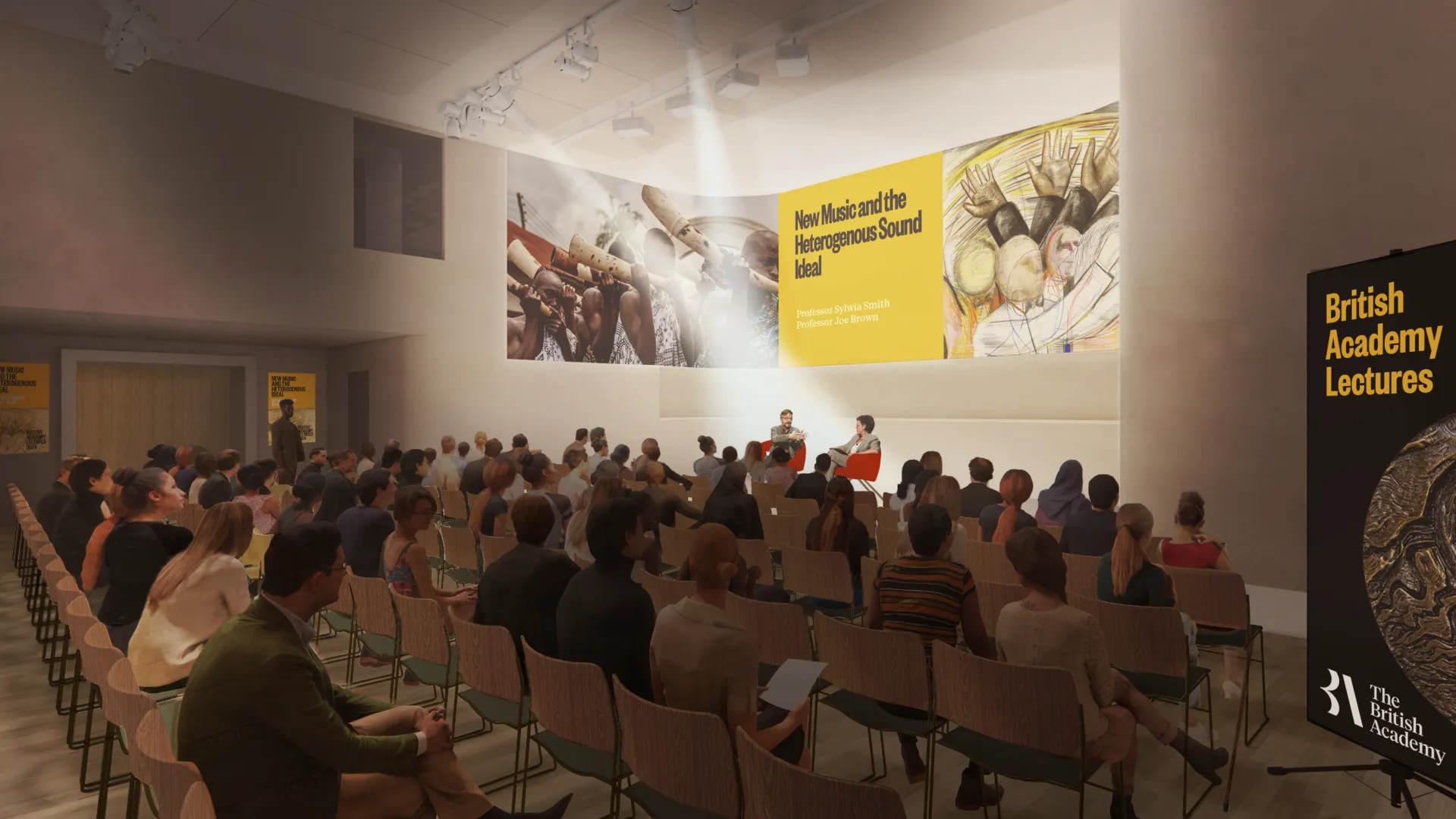 Large group of people sat in rows in a room, watching two speakers on a stage.
