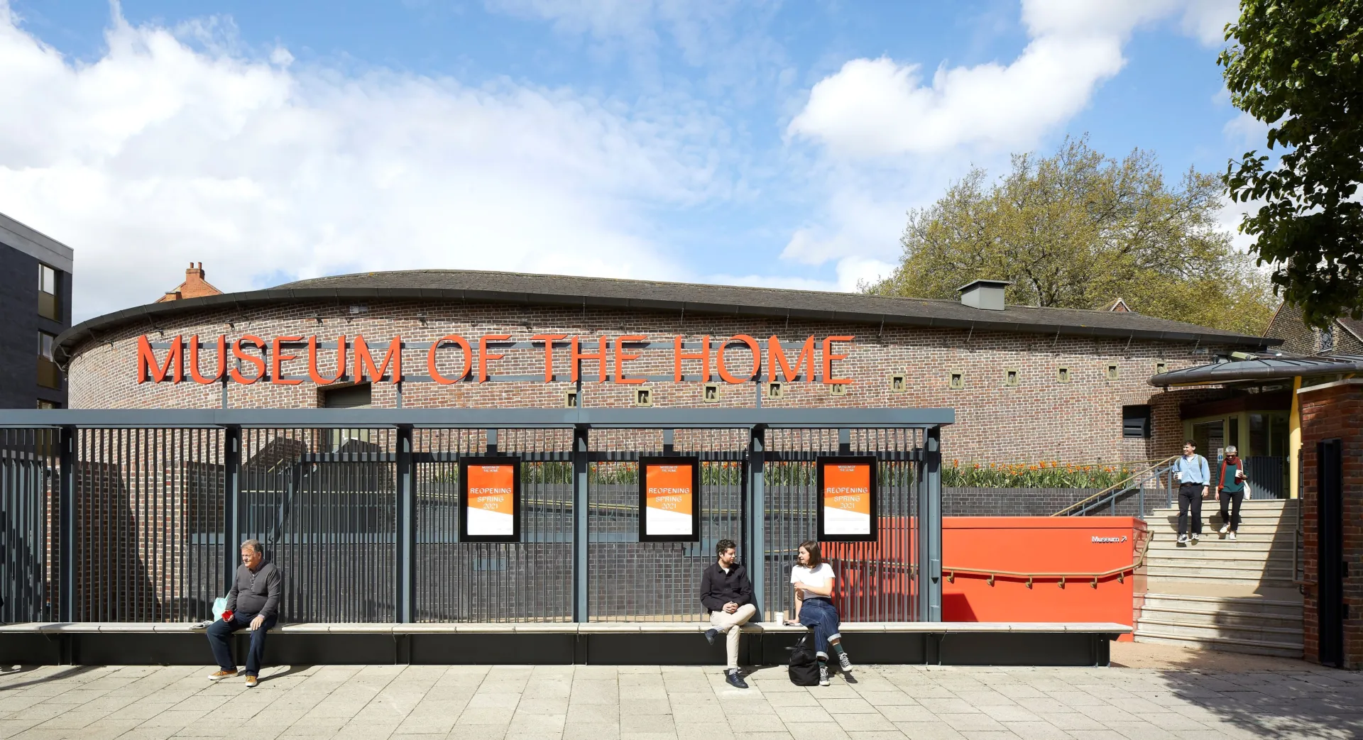 Entrance to Museum of the Home with people sitting on a bench in the foreground in Hackney London