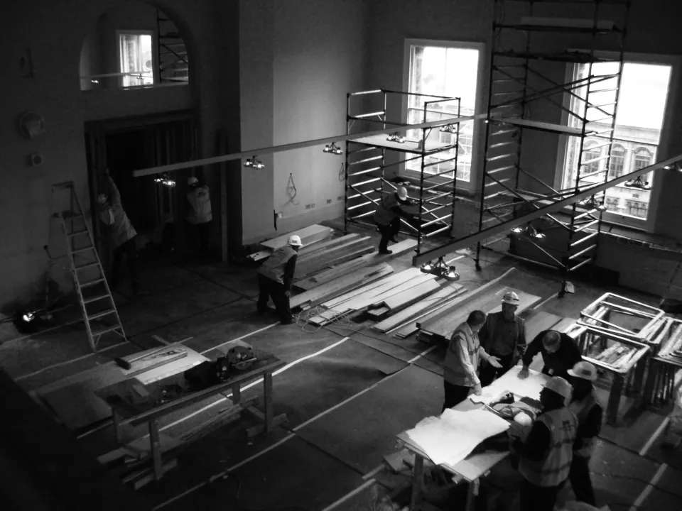 Black and white photograph of Wright & Wright architects around a table working on the construction site of the RIBA Reading Rooms at the Victoria & Albert Museum in London
