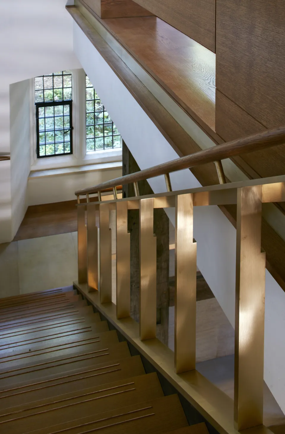 A modern stair set within historic timber beamed space.