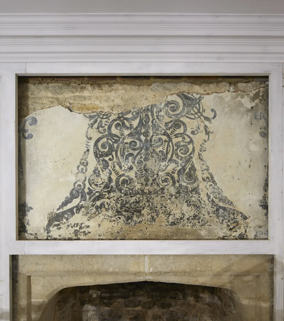 An old painted mural above a fireplace.