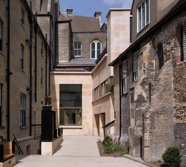 Modern stone facade of the Taylor Library between historic stone walls at Corpus Christi College at the University of Cambridge