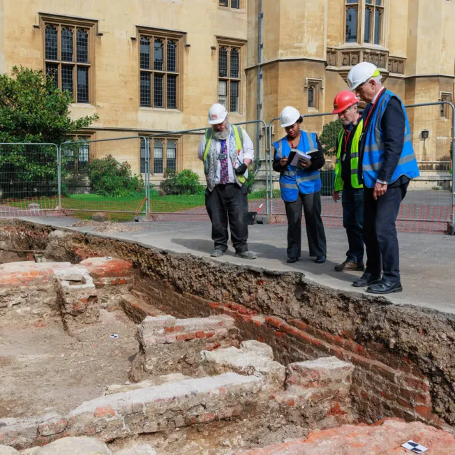 A group of people in protective wear examine archaeological remains.