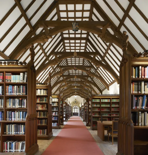 Interior of a historic library with wooden vaulted ceiling and bookshelves