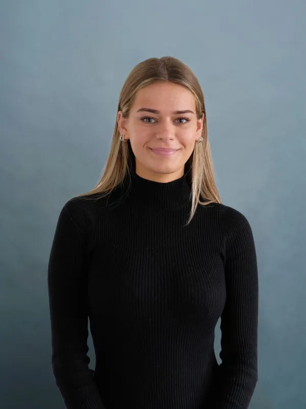 Portrait colour photograph of a woman with medium length blonde hair wearing a black turtleneck top.