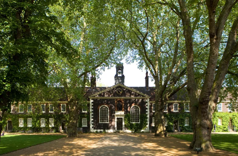 Facade of a brick building behind large trees