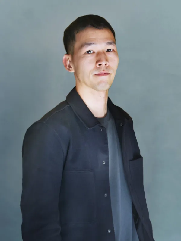 Portrait of man wearing a grey sweater in front of a grey background