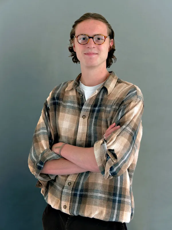 Headshot of a man in a plaid shirt against a grey background.